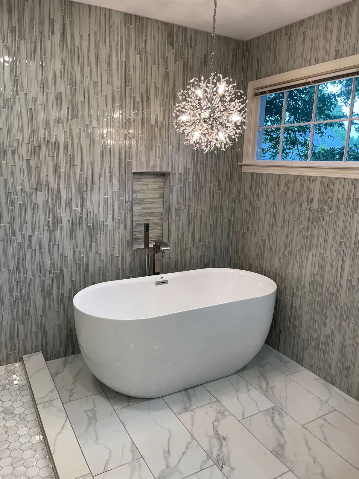 Modern bathroom with white freestanding tub and crystal chandelier